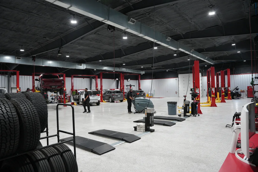 Wide view of the service workshop with vehicle lifts and tire racks.