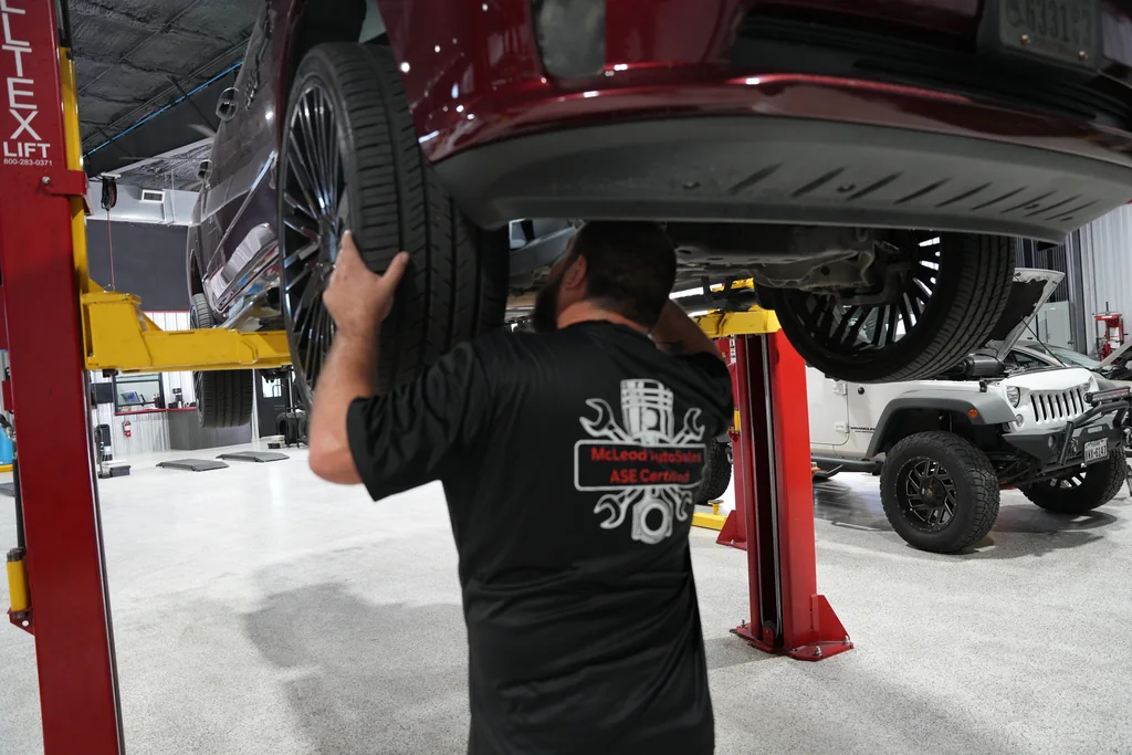 Technician looking underneath a vehicle raised on a lift.