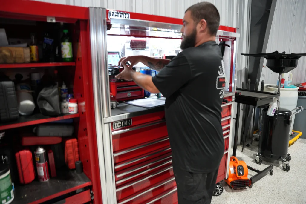 Technician selecting equipment at a red tool cabinet.