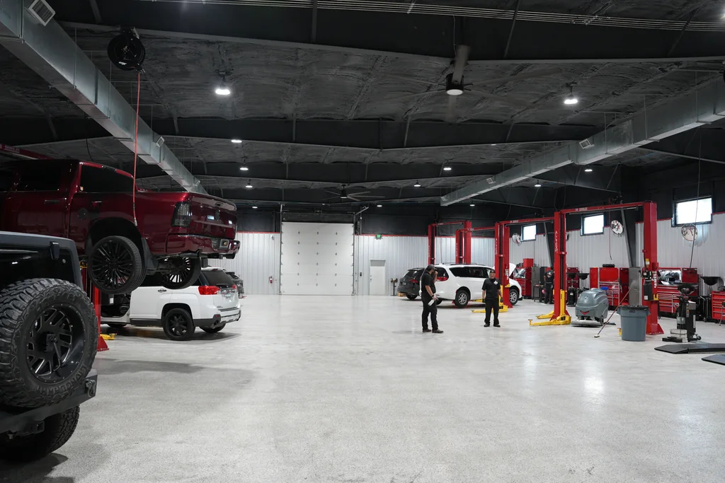 Wide workshop view with service bays, vehicles and lifts.