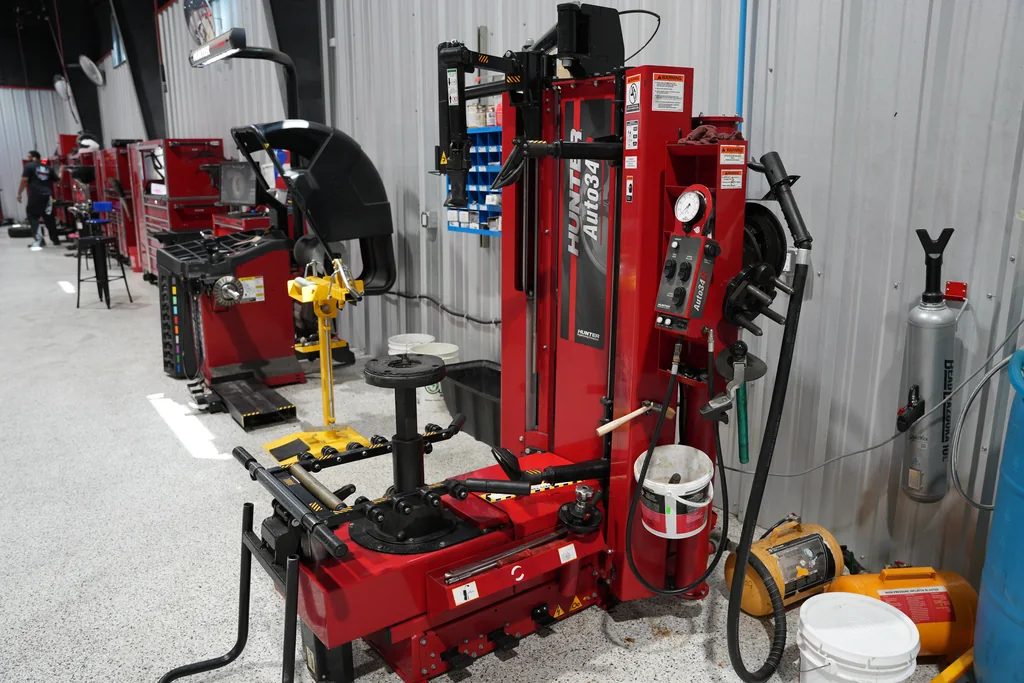Row of tire service machines and red tool cabinets in the workshop.