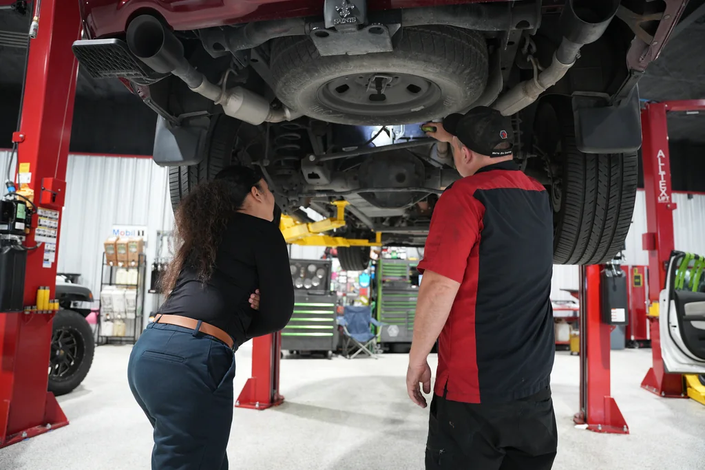 Staff examining a vehicle underbody together in the service workshop.